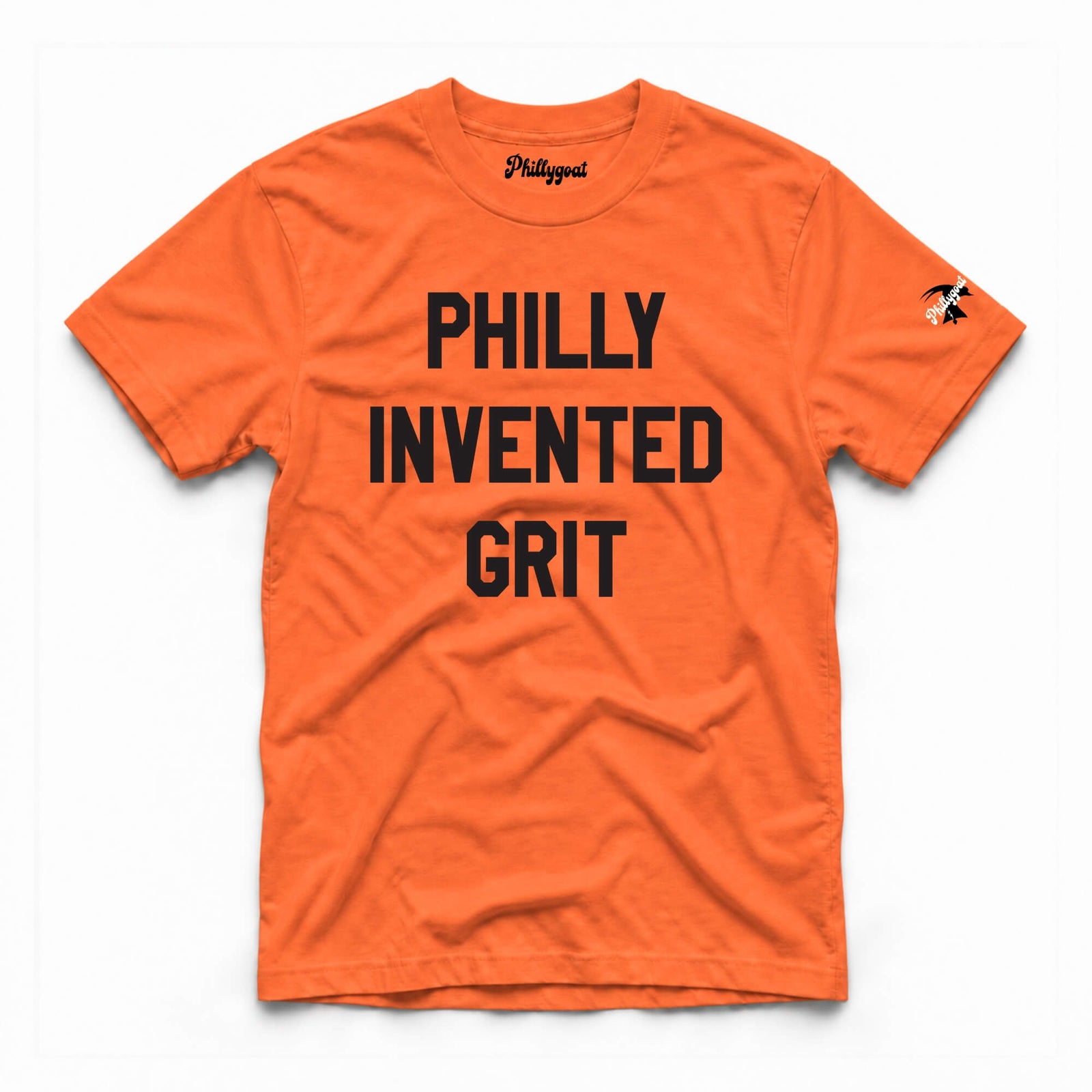 An orange short-sleeve t-shirt with the words 'PHILLY INVENTED GRIT' printed in bold black capital letters across the chest. The brand name 'Phillygoat' is visible on the inner neck label and as a small graphic on the left sleeve.