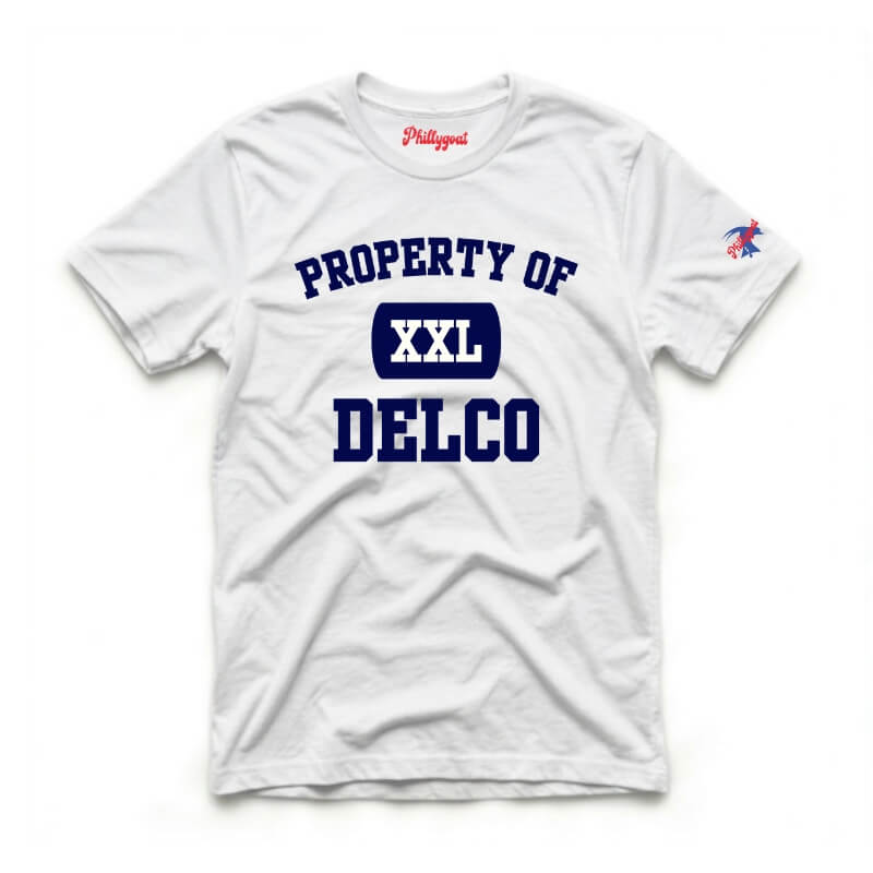 A white short-sleeve t-shirt with 'PROPERTY OF DELCO' printed in navy blue on the front, featuring a navy blue 'XXL' block in the center and a small red and blue Philadelphia logo on the left sleeve.