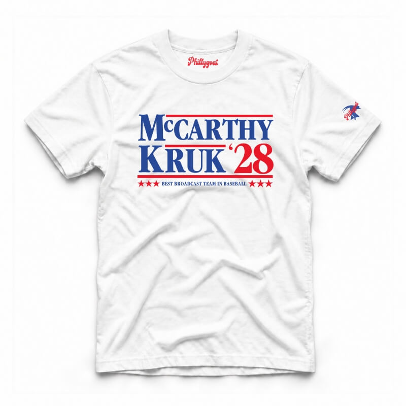 A white short-sleeve t-shirt with a red and blue graphic reading 'McCarthy Kruk '28' across the chest, plus a small red script logo inside the collar and a small multicolor bird emblem on the sleeve.