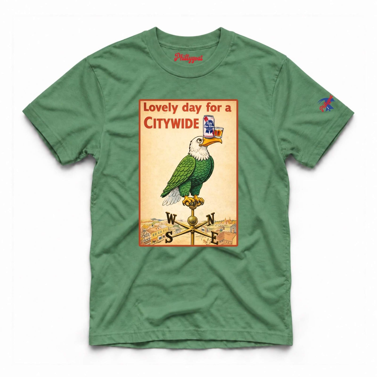A green crewneck t-shirt featuring a vintage-style citywide eagle poster graphic on the front, with a compass rose and the words 'Lovely day for a CITYWIDE'. The brand name 'Pigeon' is printed inside the collar, and a small multicolor logo is on the right sleeve.