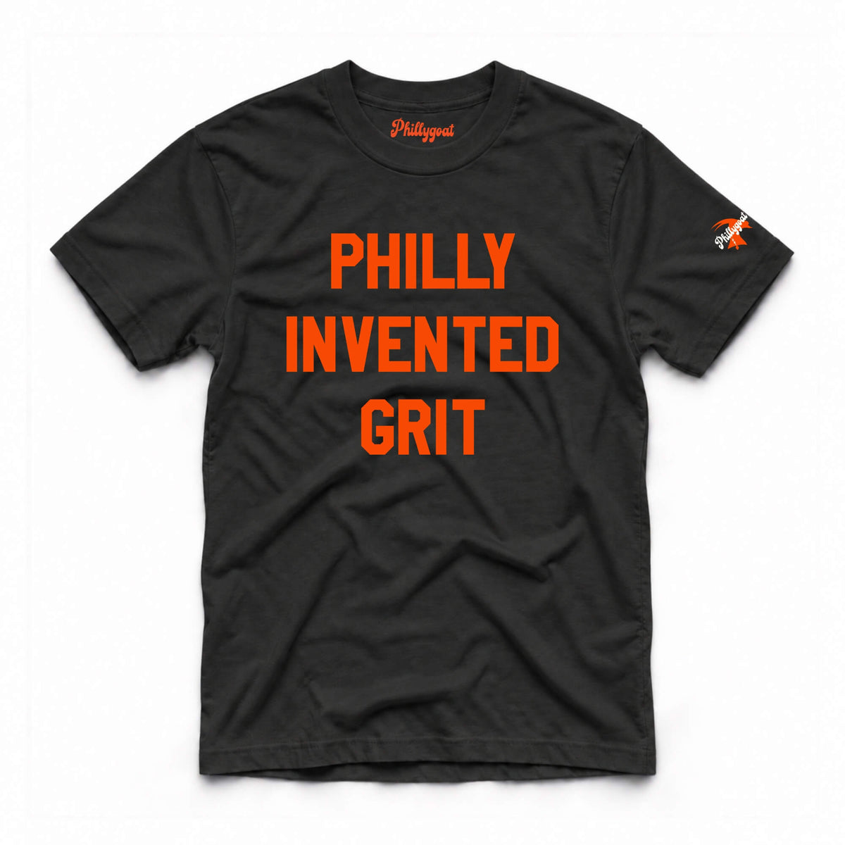 A black short-sleeve t-shirt with 'PHILLY INVENTED GRIT' printed in bold orange letters across the chest, featuring a small orange and white logo on the right sleeve and a small orange script logo inside the collar, displayed on a clean white background.